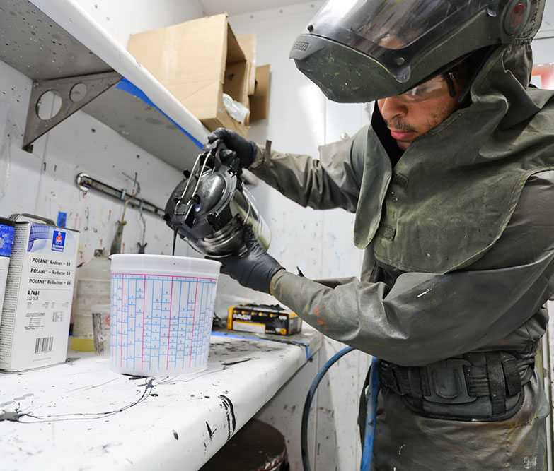 man in protective suit mixing paint