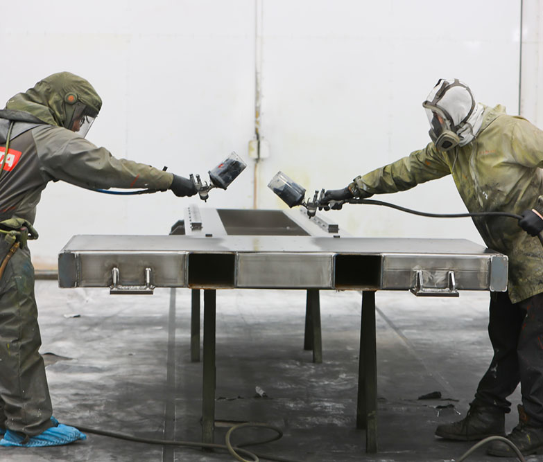 two individuals painting metal